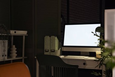 Karanlık ofisteki dizinlerle parlayan bilgisayar monitörü
