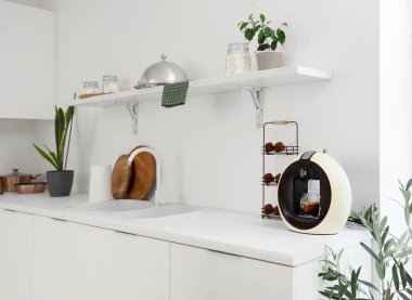Mutfak masasında kapsülleri ve damlayan espresso ile modern kahve makinesi.