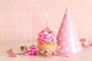 Beyaz masasında yanan mum ve parti şapkası olan tatlı bir kek.