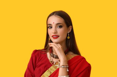 Sarı arka planda sarili güzel bir Hintli kadın.