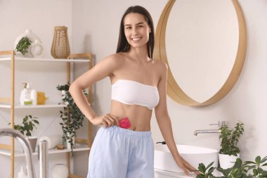 Banyoda prezervatifli genç bir kadın.