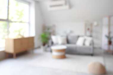 Gri kanepe, masa ve raf üniteleriyle oturma odasının bulanık görüntüsü