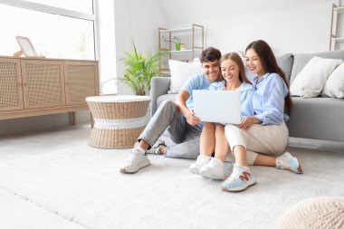 Evde dizüstü bilgisayar kullanan iki kadınla genç bir adam. Poliyamory konsepti