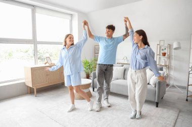 Evde iki kadınla dans eden genç bir adam. Poliyamory konsepti