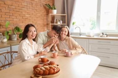 Mutfakta masada iki kadınla oturan genç bir adam. Poliyamory konsepti