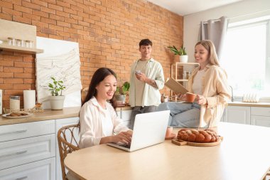 İki kadınla birlikte mutfakta vakit geçiren genç bir adam. Poliyamory konsepti