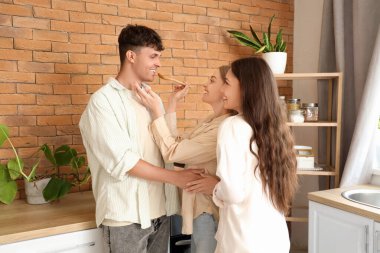 Mutfakta iki kadınla yemek yiyen genç bir adam. Poliyamory konsepti