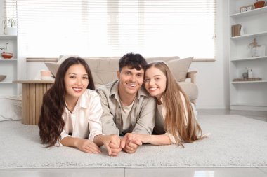 Evde yerde yatan iki kadınla birlikte genç bir adam. Poliyamory konsepti