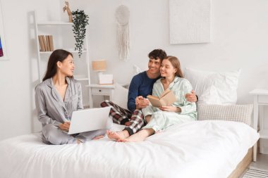 İki kadınla birlikte yatak odasında vakit geçiren genç bir adam. Poliyamory konsepti