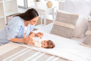 Anne yatak odasında bebeğinin elini tutuyor.