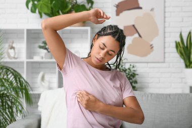 Genç Afro-Amerikalı kadın evde göğüslerini kontrol ediyor. Kanser farkındalığı kavramı