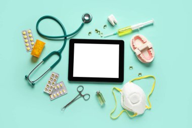 Yeşil arka planda tıbbi malzemeleri olan bir tablet bilgisayar. Teletıp kavramı