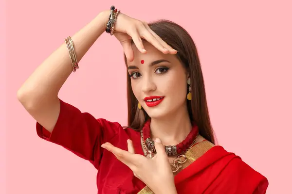 stock image Beautiful young happy Indian woman in sari dancing on pink background