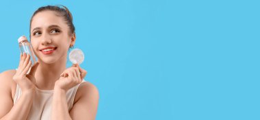 Mavi zemin üzerinde mikiler suyu ve pamuk pedi tutan genç bir kadın.