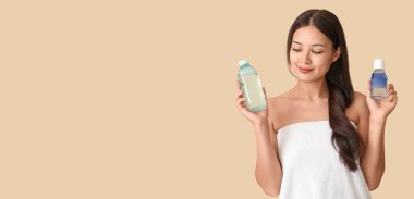 Genç Asyalı bir kadın bej arka planda su şişeleri tutuyor ve mesaj için yer var.