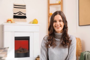 Sonbahar günü evde gülümseyen genç kadın.