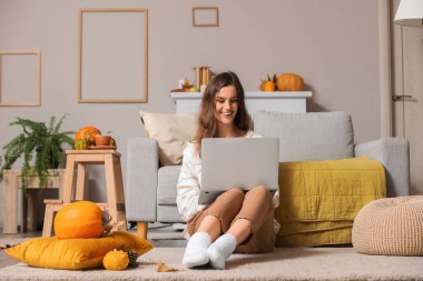 Evde dizüstü bilgisayar kullanan genç bir kadın.