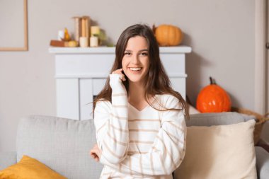 Evdeki kanepede oturan genç bir kadın.