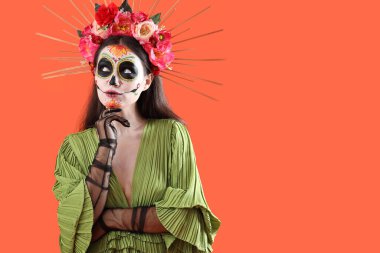 Cadılar Bayramı için turuncu arka planda giyinmiş düşünceli genç bir kadın.