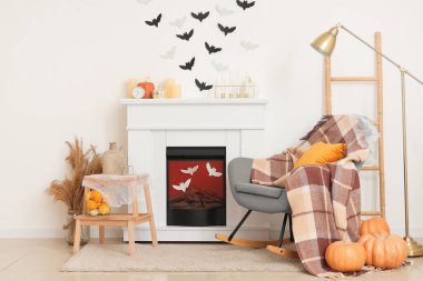 Cadılar Bayramı için dekore edilmiş oturma odasının içinde şömine, sallanan sandalye ve kağıt yarasalar var.