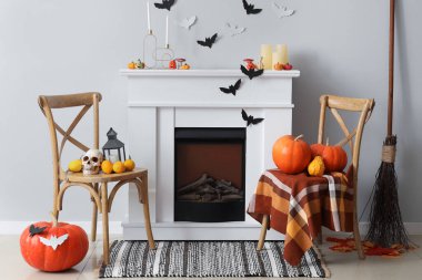 Cadılar Bayramı için dekore edilmiş oturma odasının içinde şömine, sandalye ve kağıt yarasalar var.