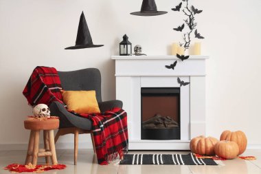 Cadılar Bayramı için dekore edilmiş oturma odasının içinde şömine ve koltuk var.