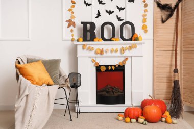 Cadılar Bayramı için dekore edilmiş oturma odasının içinde şömine ve koltuk var.