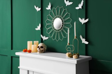 Halloween pumpkins with skull and candles on mantelpiece in room clipart