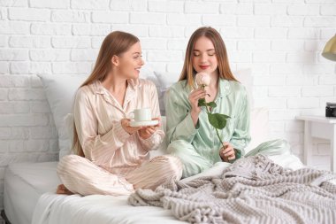 Genç lezbiyen kadın yatak odasında karısından gül ve kahve alıyor.
