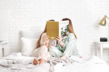 Yatak odasında dergisi olan genç lezbiyen çift.