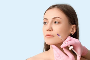 Güzel kadın mavi arka planda iğne oluyor, yakın plan.