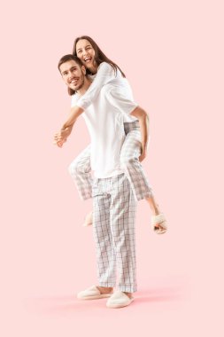 Pembe arka planda pijamalı mutlu bir çift.