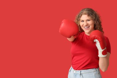 Kırmızı arka planda boks eldivenli güzel, genç bir kadın.