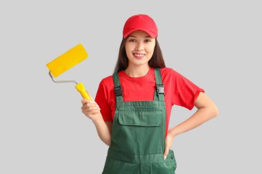 Gri arka planı olan genç bir kadın ressam.