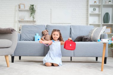 Evinde ilk yardım çantası, steteskop ve İngiliz kedisi olan sevimli küçük bir kız.
