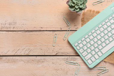 Tahta arka planda Cyan bilgisayar klavyesi, klipler ve ev bitkileri