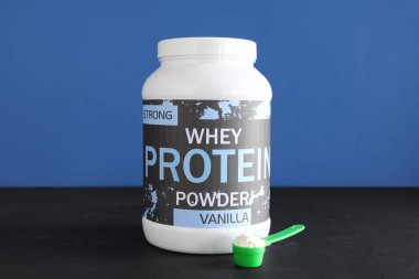 Renk arkaplanına karşı protein tozu ve kepçeyle dolu şişe