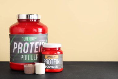 Koyu renkli masa üzerinde protein tozu bulunan şişeler ve kepçeler renk arka planına karşı