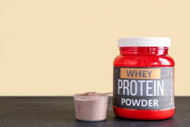 Şişe ve kepçe protein tozu ile koyu masa üzerinde renk arka planı karşı