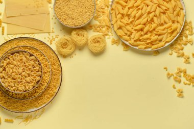 Bej arka planda farklı türde pişmemiş makarna içeren kaseler.