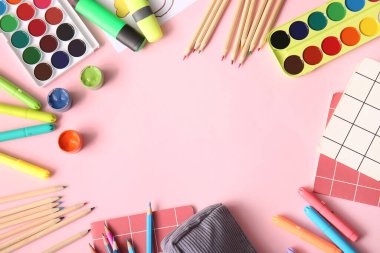 Renkli kalemler, keçeli kalemler ve pembe arkaplandaki not defterlerinden yapılmış çerçeveler