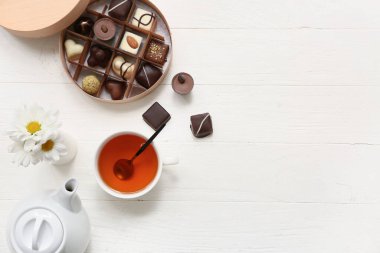 Şekerleme kutusu, bir fincan çay ve ahşap arka planda çaydanlık.