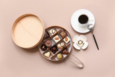 Lezzetli çikolata şekerlemeleri, mutfak maşaları, kahverengi arka planda bir fincan kahve ve kaşık.