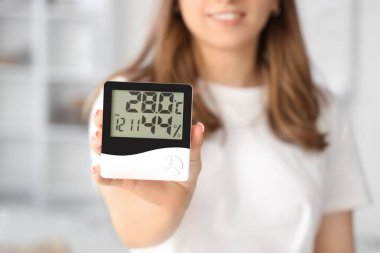 Evde dijital higrometresi olan kadın, yakın plan.