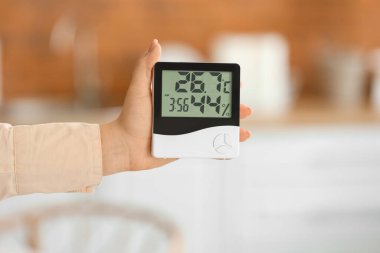 Mutfakta dijital higrometresi olan kadın, yakın plan.