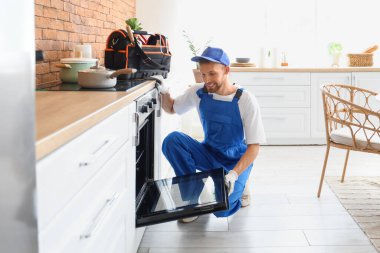 Erkek teknisyen mutfakta bozuk fırını kontrol ediyor.