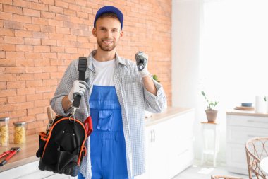 Mutfakta alet çantası ve el feneri olan bir erkek teknisyen.