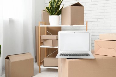 Işık odasında kutuları taşıyan boş dizüstü bilgisayar, kapat