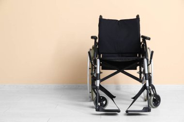 Bej duvarın yanındaki boş tekerlekli sandalye.