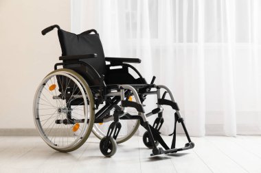 Odanın penceresinin yanındaki boş tekerlekli sandalye.